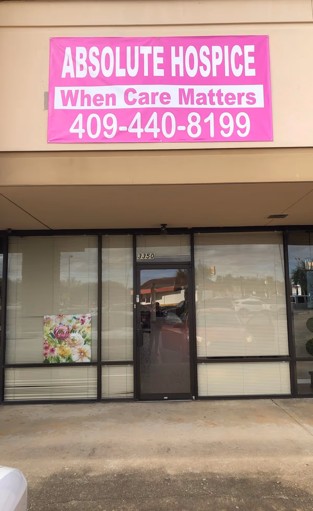 Front view of Absolute Hospice storefront with pink banner and glass entrance.