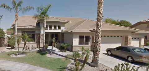 Front exterior of Fletcher Heights Assisted Living, with palm trees, a two-car driveway, and entrance.