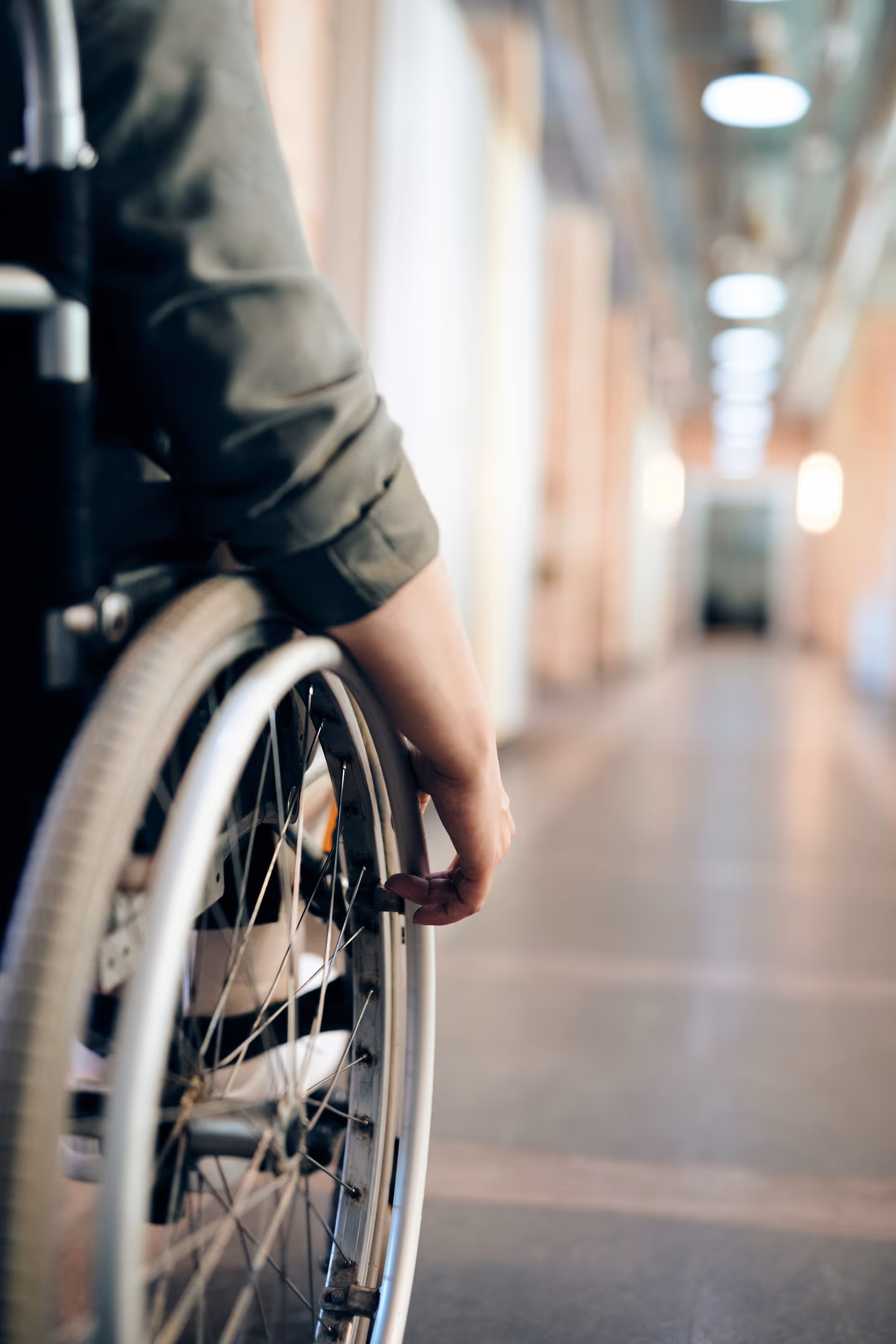 Close-up of a wheelchair along a brightly lit interior hallway in a care facility.