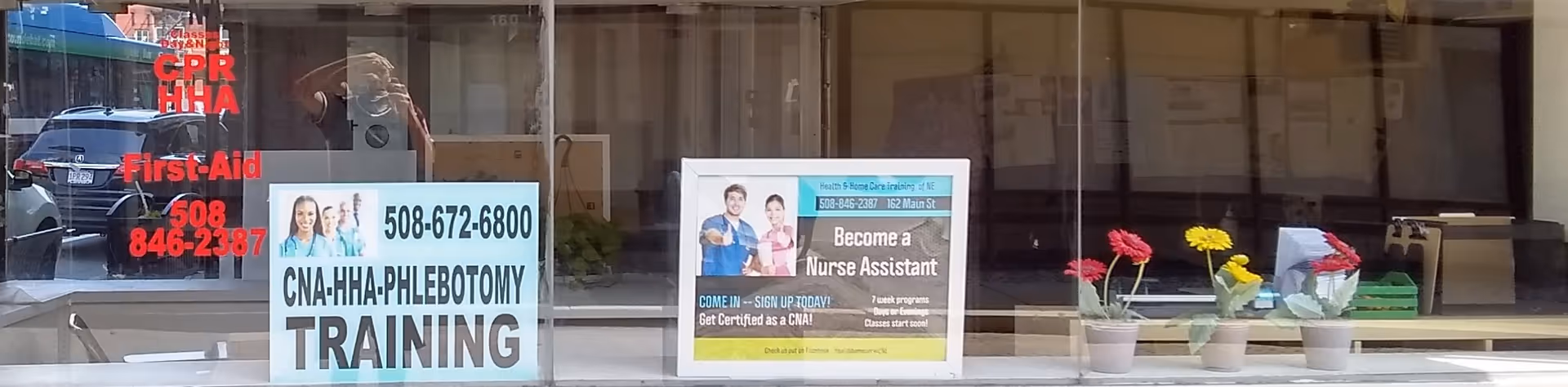 Storefront of Brockton Home Health Agency with training signs and potted flowers.