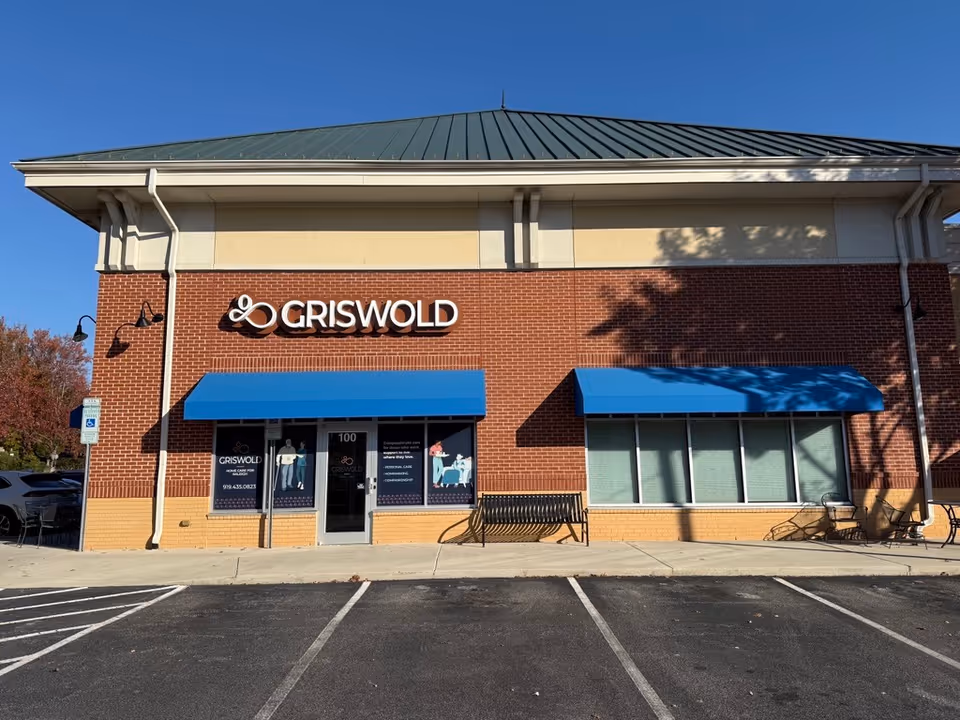 Brick storefront with Griswold sign and blue awnings in parking lot
