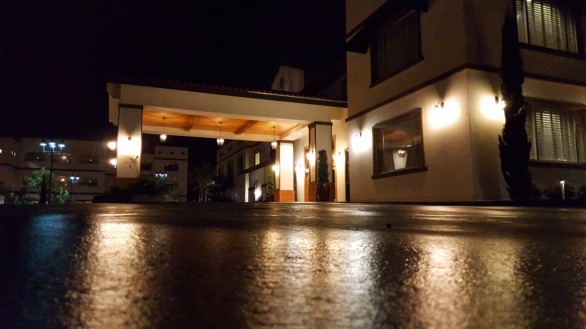 Night exterior of Clearwater at South Bay entrance with illuminated canopy and wet pavement.