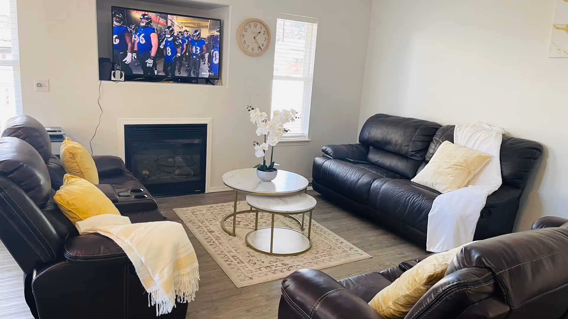 Cozy living room with dark leather couches, a coffee table, TV, and fireplace.