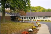Exterior view of Complete Care at Corsica Hills with a curved walkway and flowers.