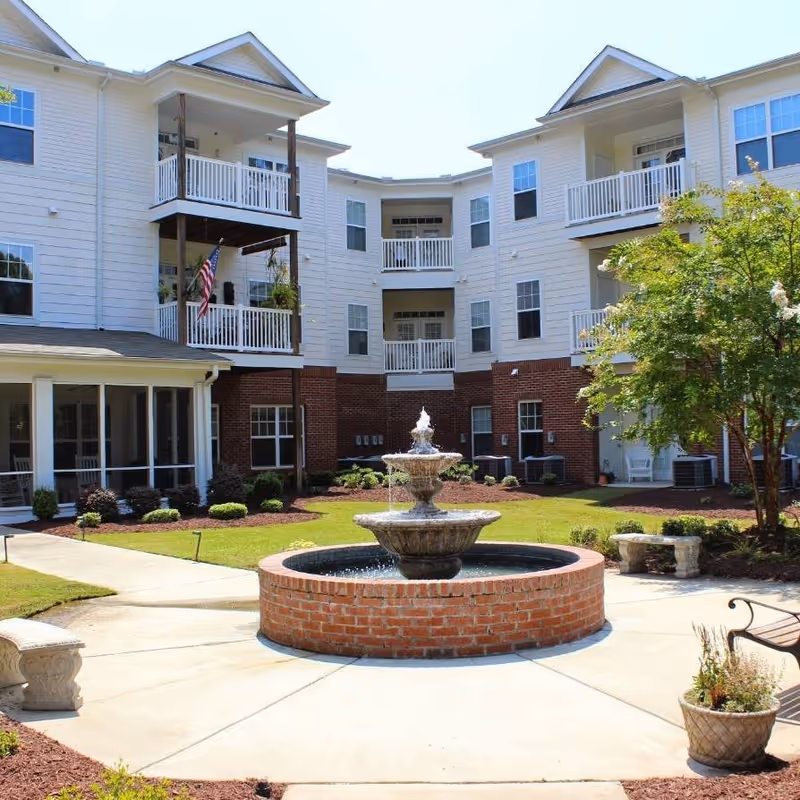Courtyard with a central tiered fountain, benches, and a three-story residence with balconies.