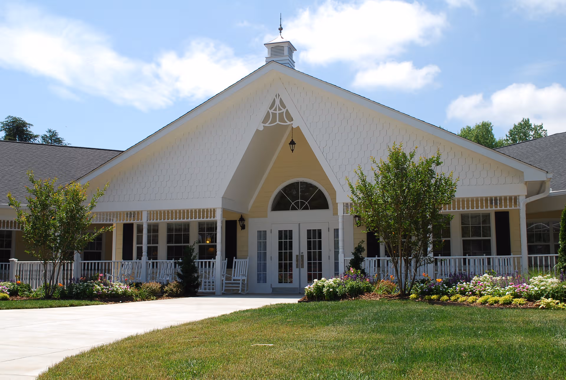 Carillon Assisted Living front entrance with rocking chairs and landscaped garden.