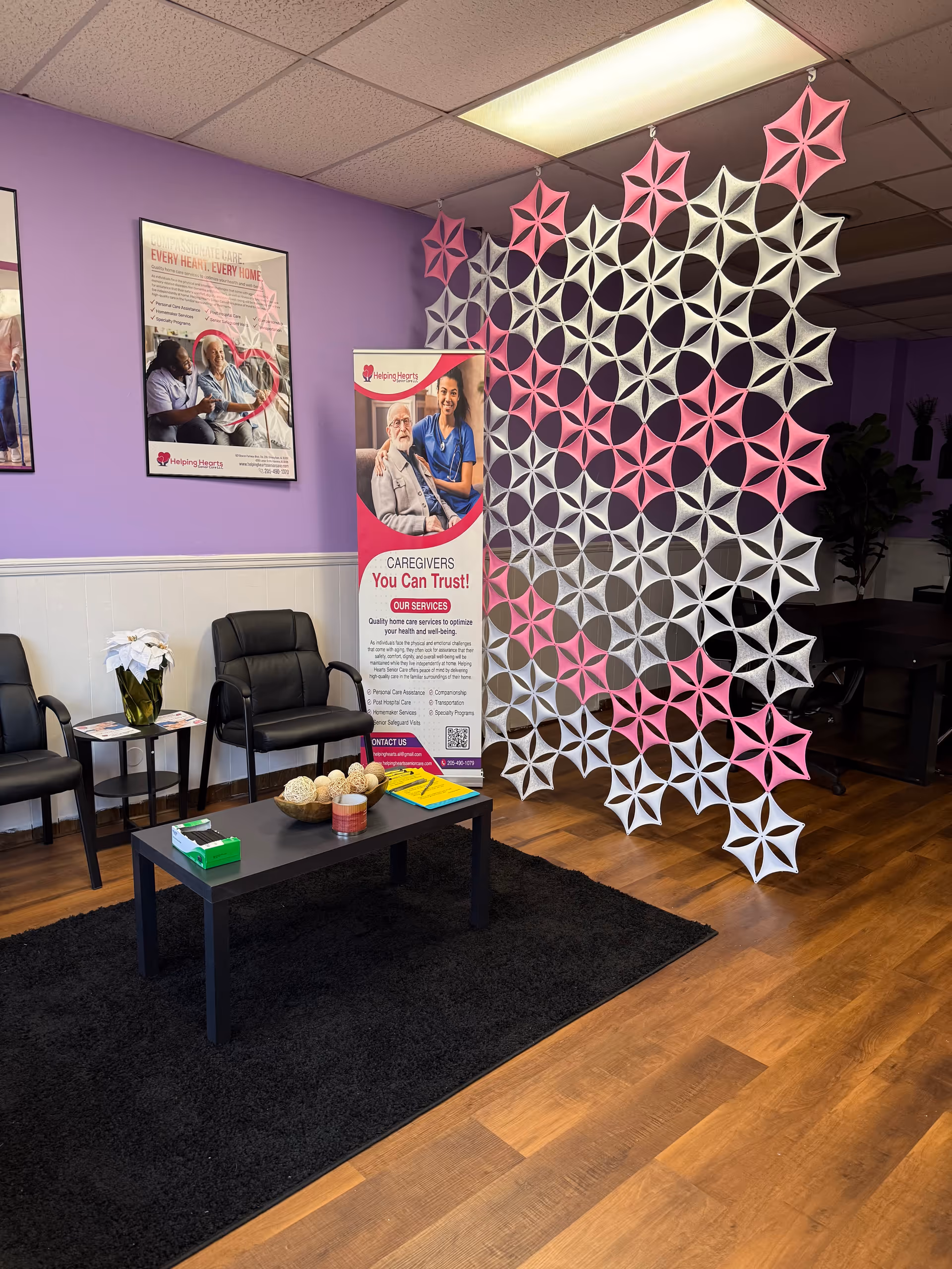 Interior lobby of a senior care facility with chairs, a banner, and pink-white decorative screen.