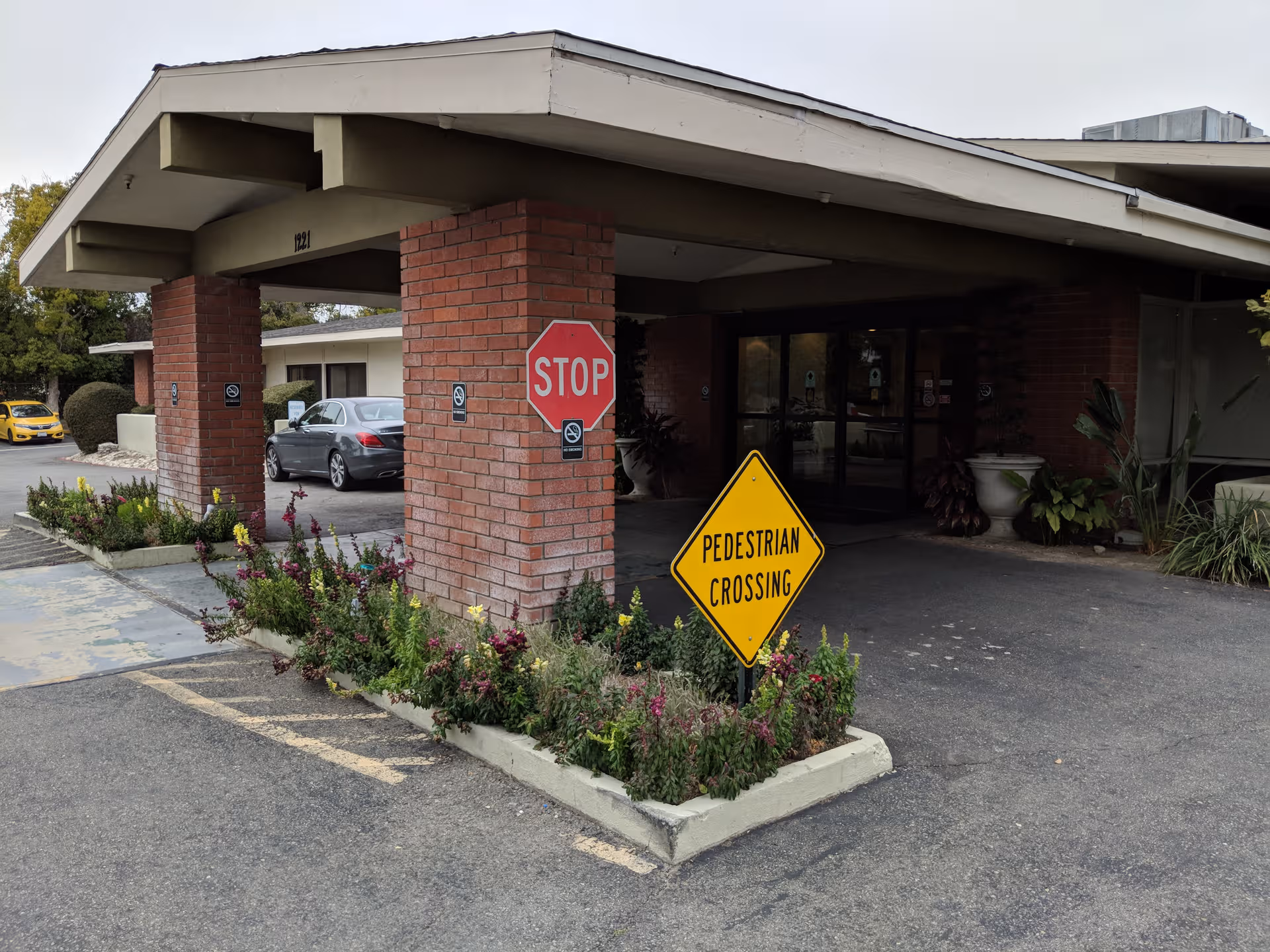 Exterior view of Upland Rehabilitation and Care Center entrance with stop and pedestrian crossing signs.