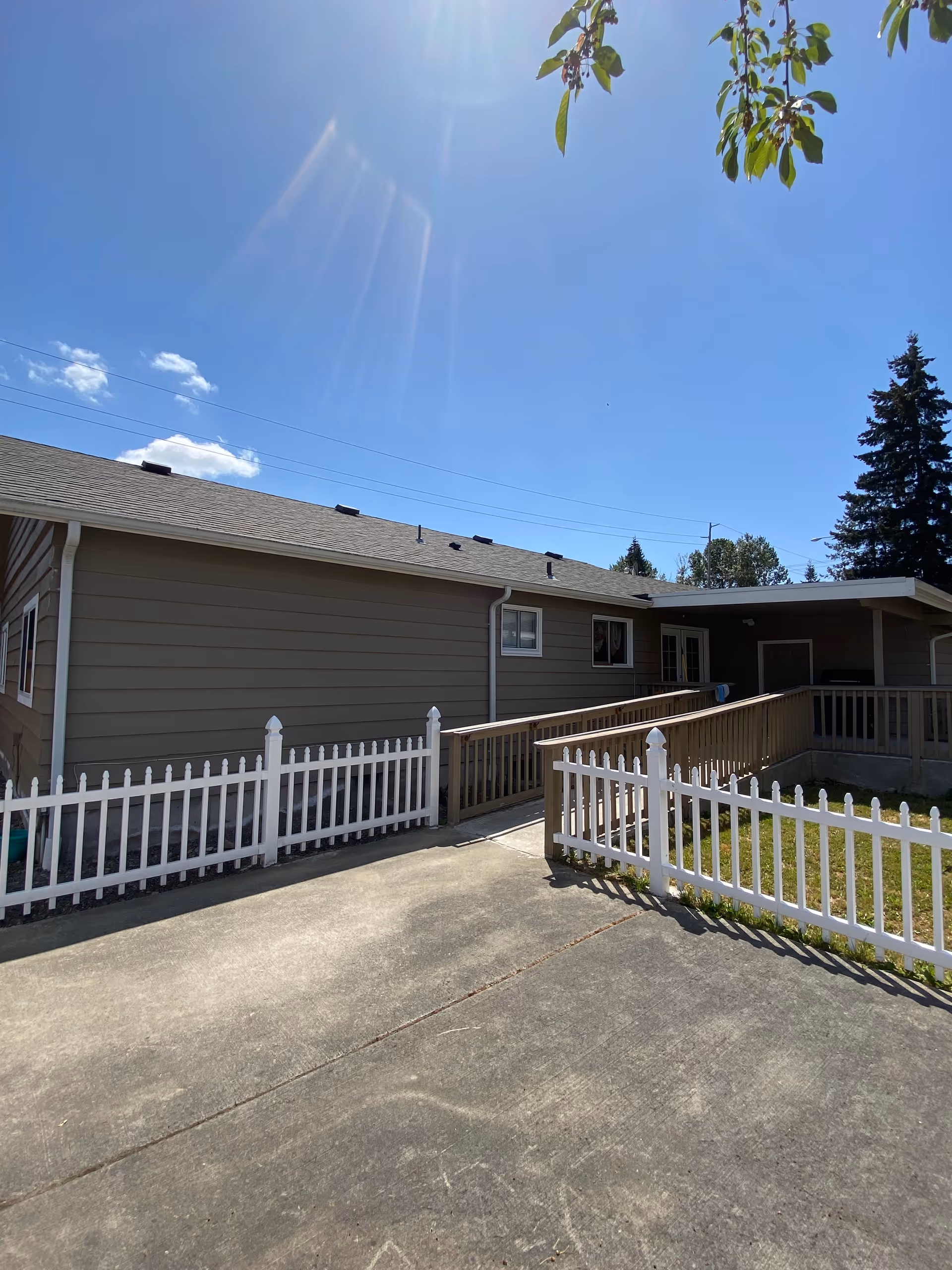Single-story facility exterior with a concrete path, white picket fences, and a ramp.