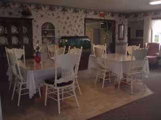 Indoor dining room with round tables, white chairs, and floral wallpaper.
