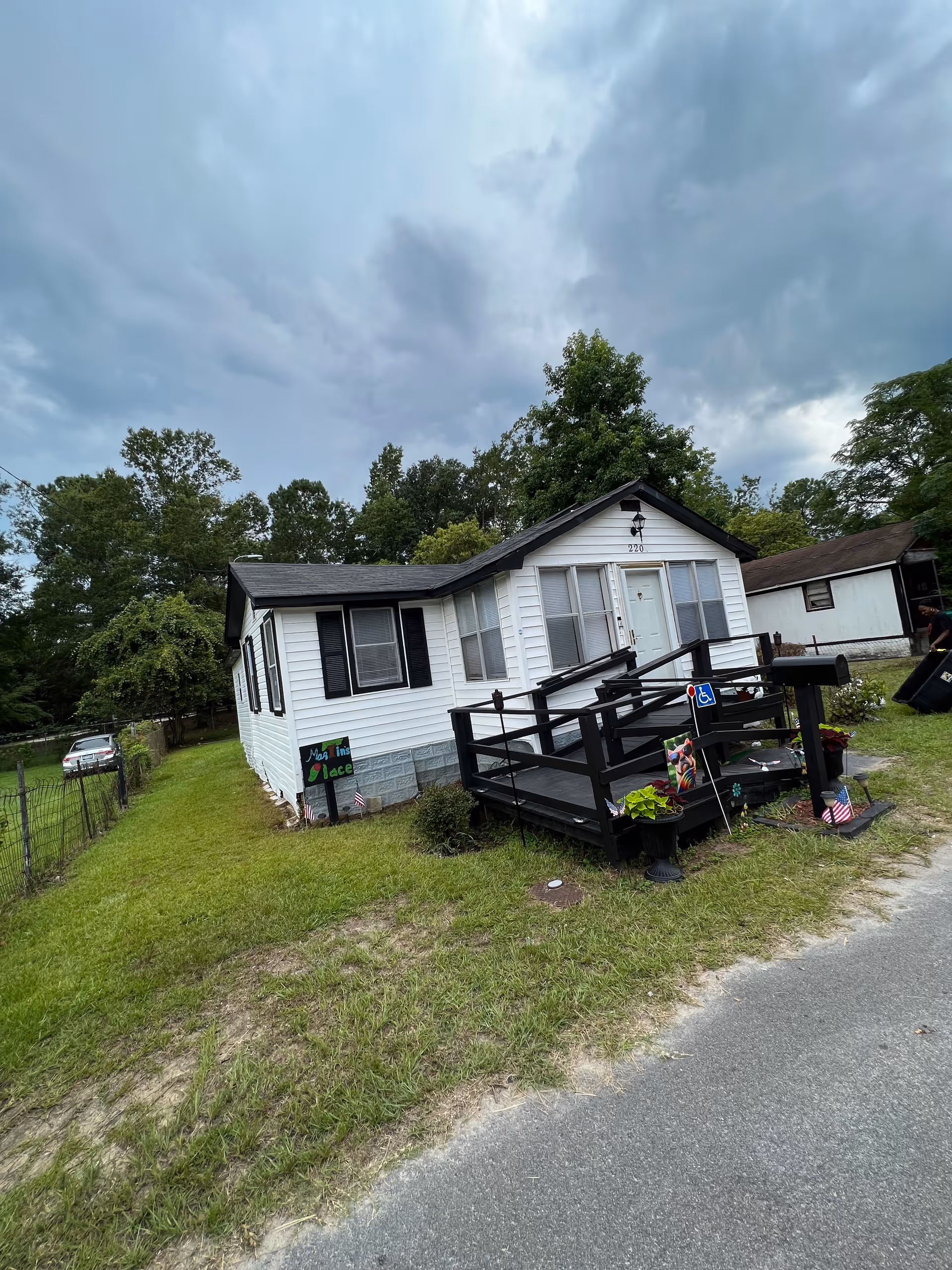 Front view of a small white assisted living home with a wheelchair ramp and sign.