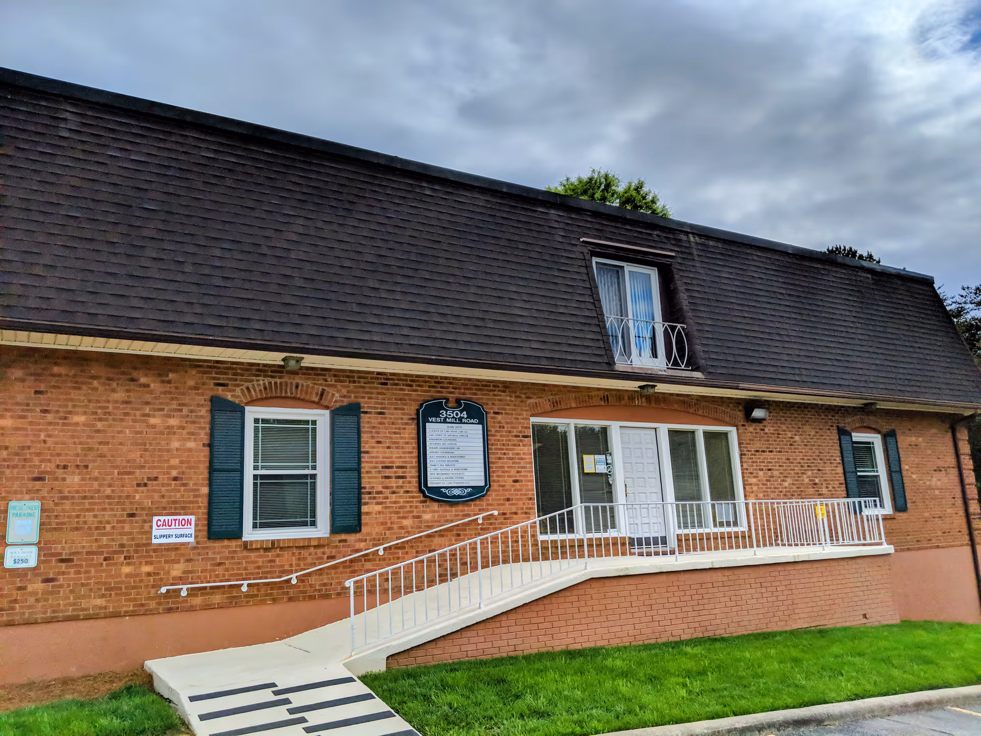 Brick senior living facility frontage with ramped entrance and white railing.