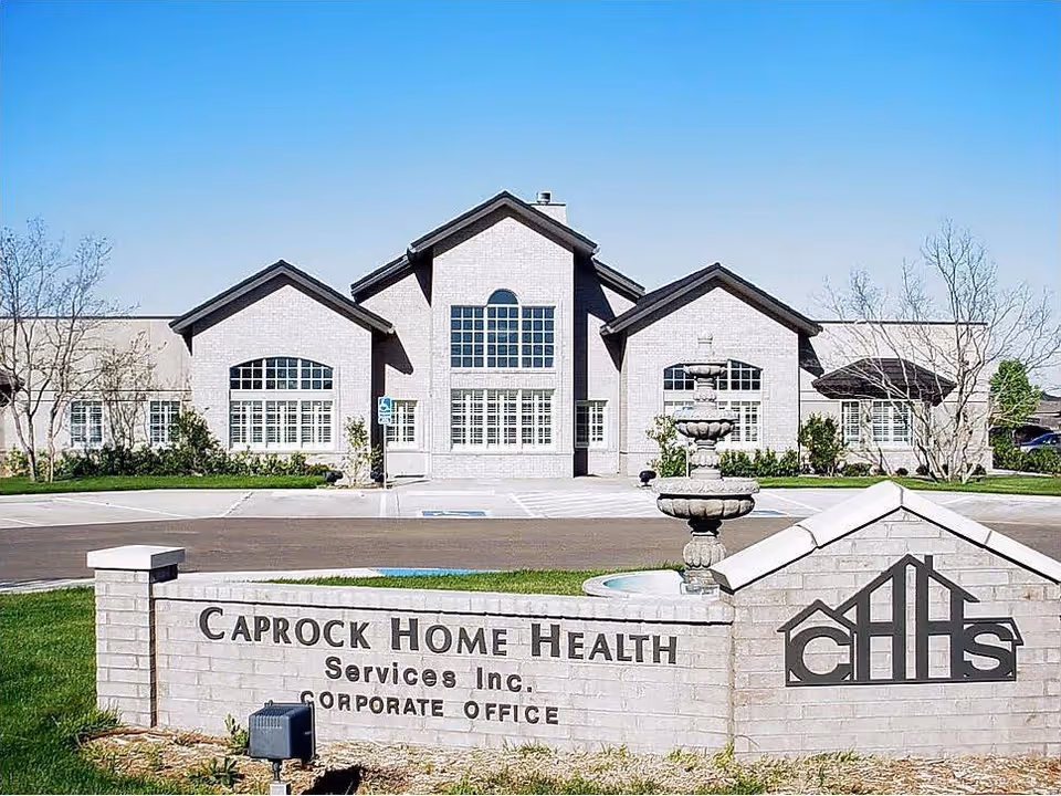 A brick corporate office building for Caprock Home Health Services with a stone sign and fountain.