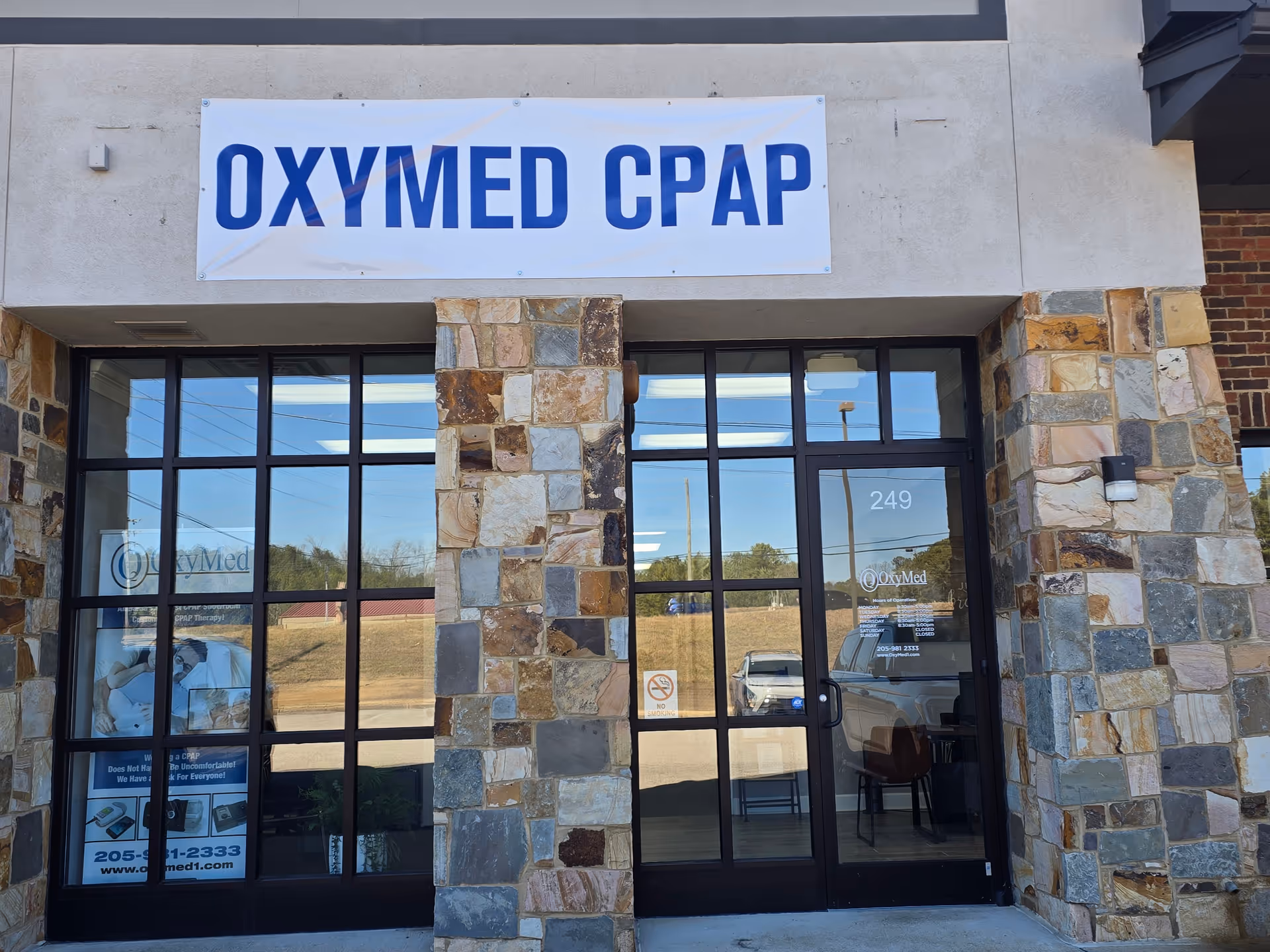 Stone-clad building entrance with large glass doors and a prominent OXYMED CPAP sign.