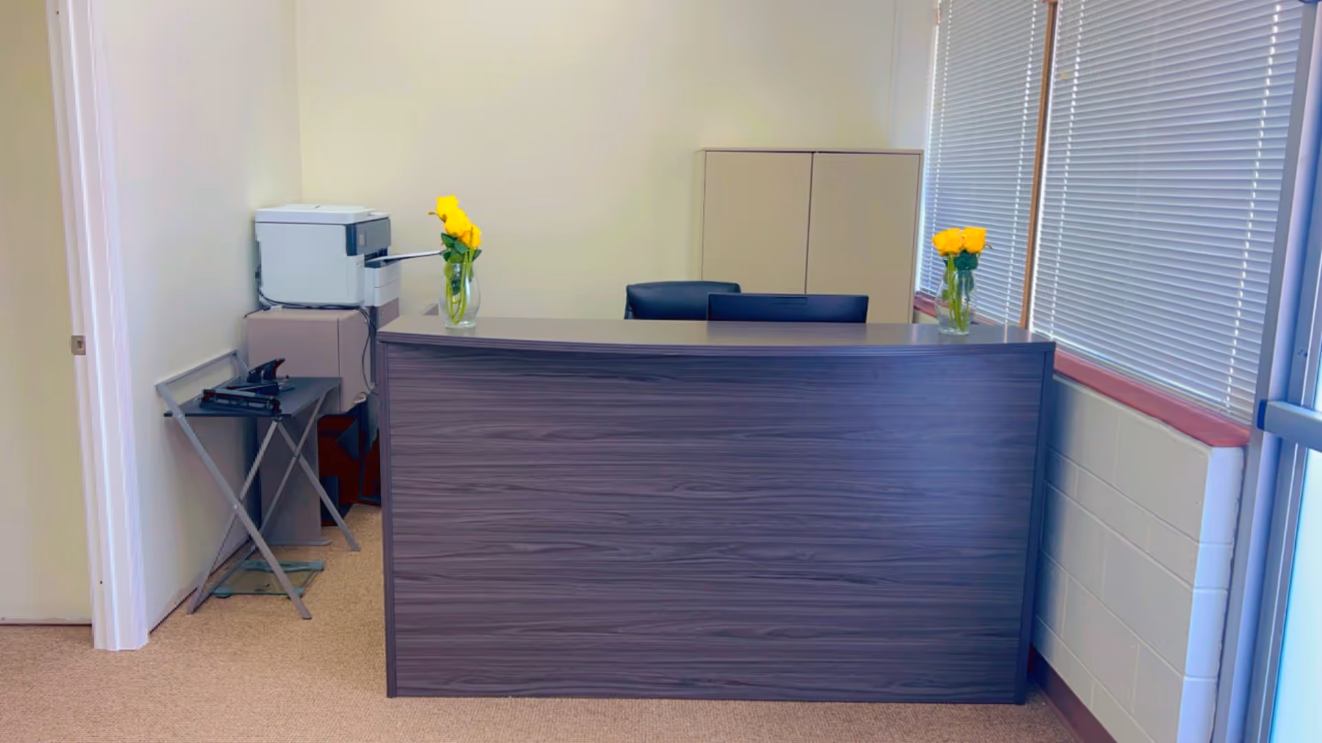 Reception desk with yellow flowers in a quiet interior lobby.