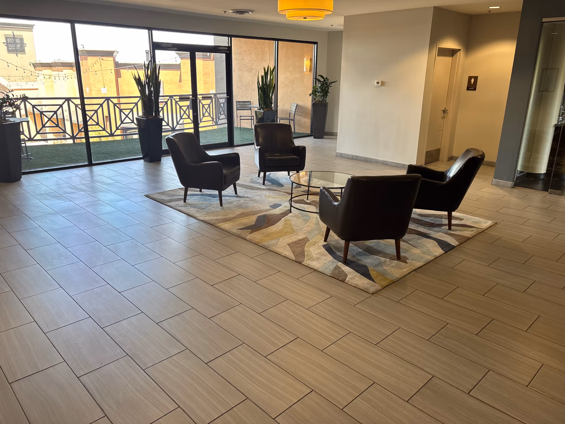 Modern senior living facility lounge with four black chairs around a glass coffee table.