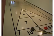 Indoor hallway floor features a triangular numbered game board with lines.