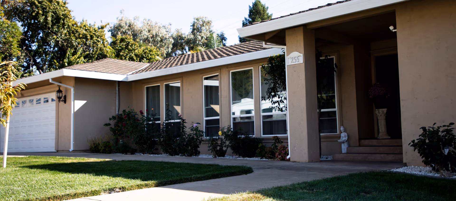 Front view of a single-story senior care facility with lawn and walkway.