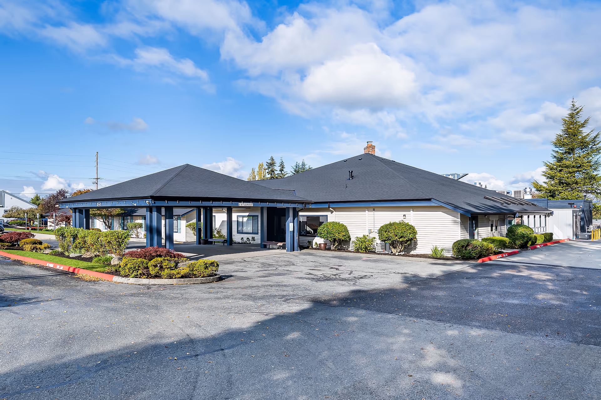 Logan Creek Retirement Community building with a covered entrance and trimmed shrubs.