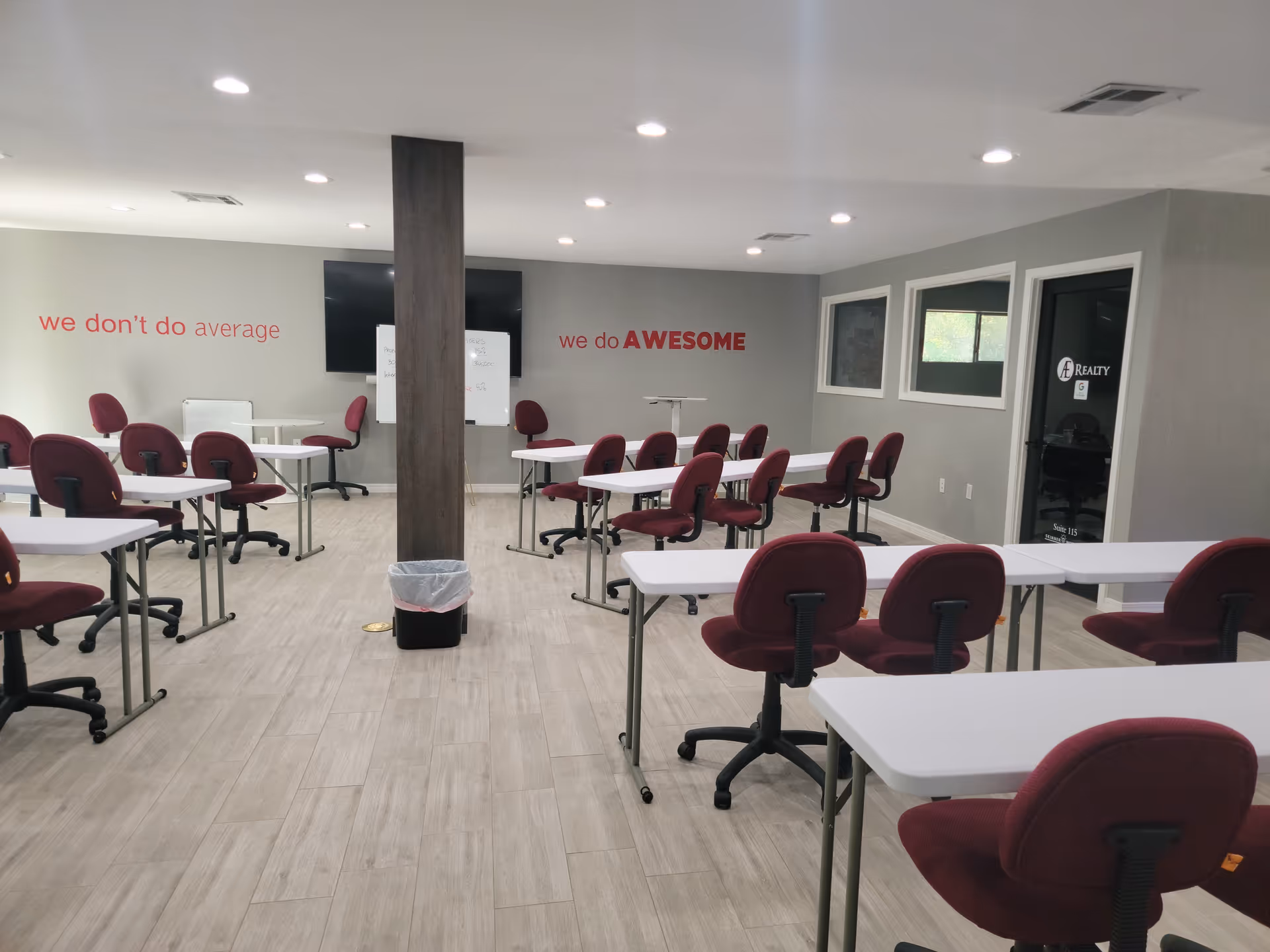 Spacious training room with white desks, maroon chairs, and motivational wall quotes.