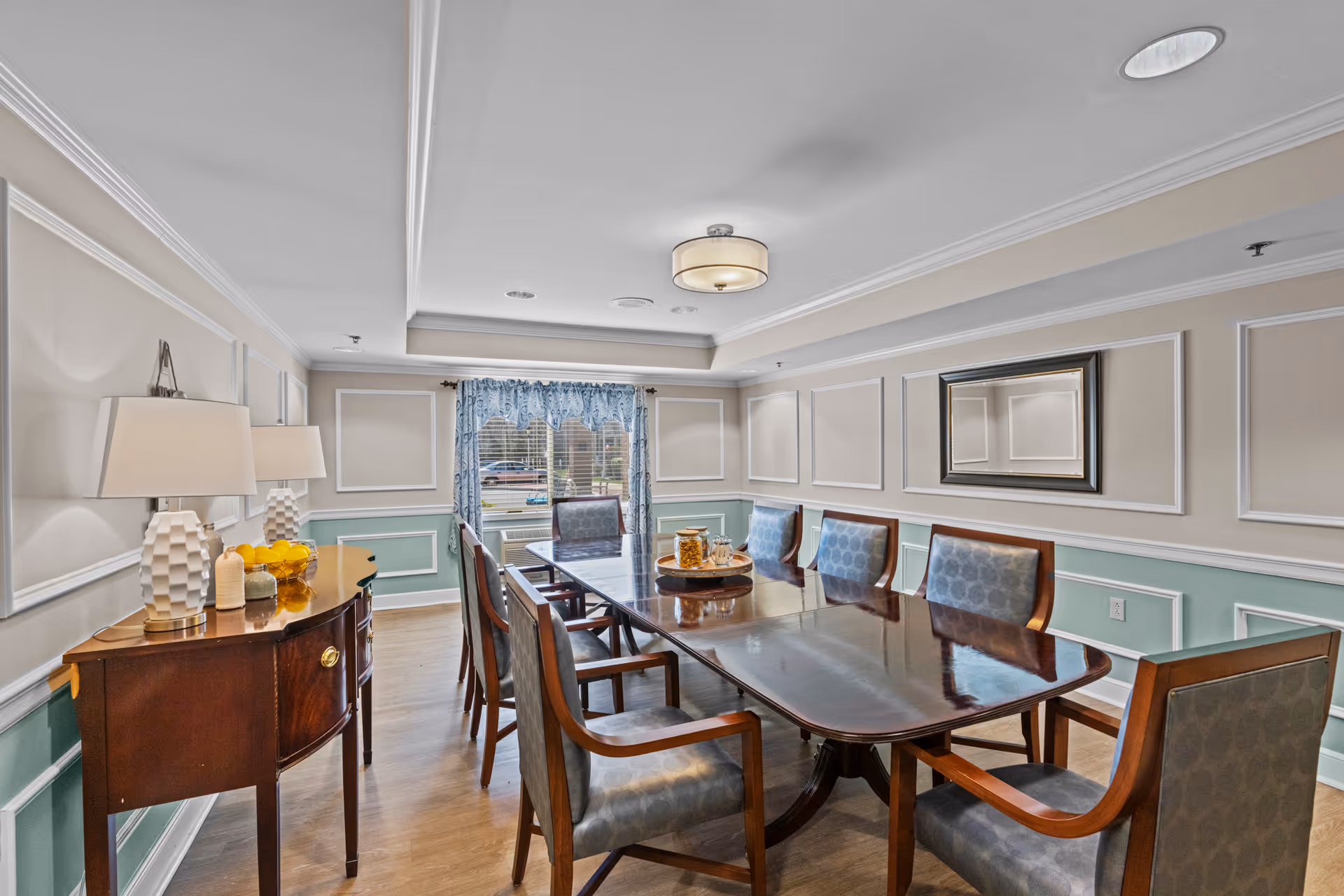 A formal dining room with a long wooden table and upholstered chairs.