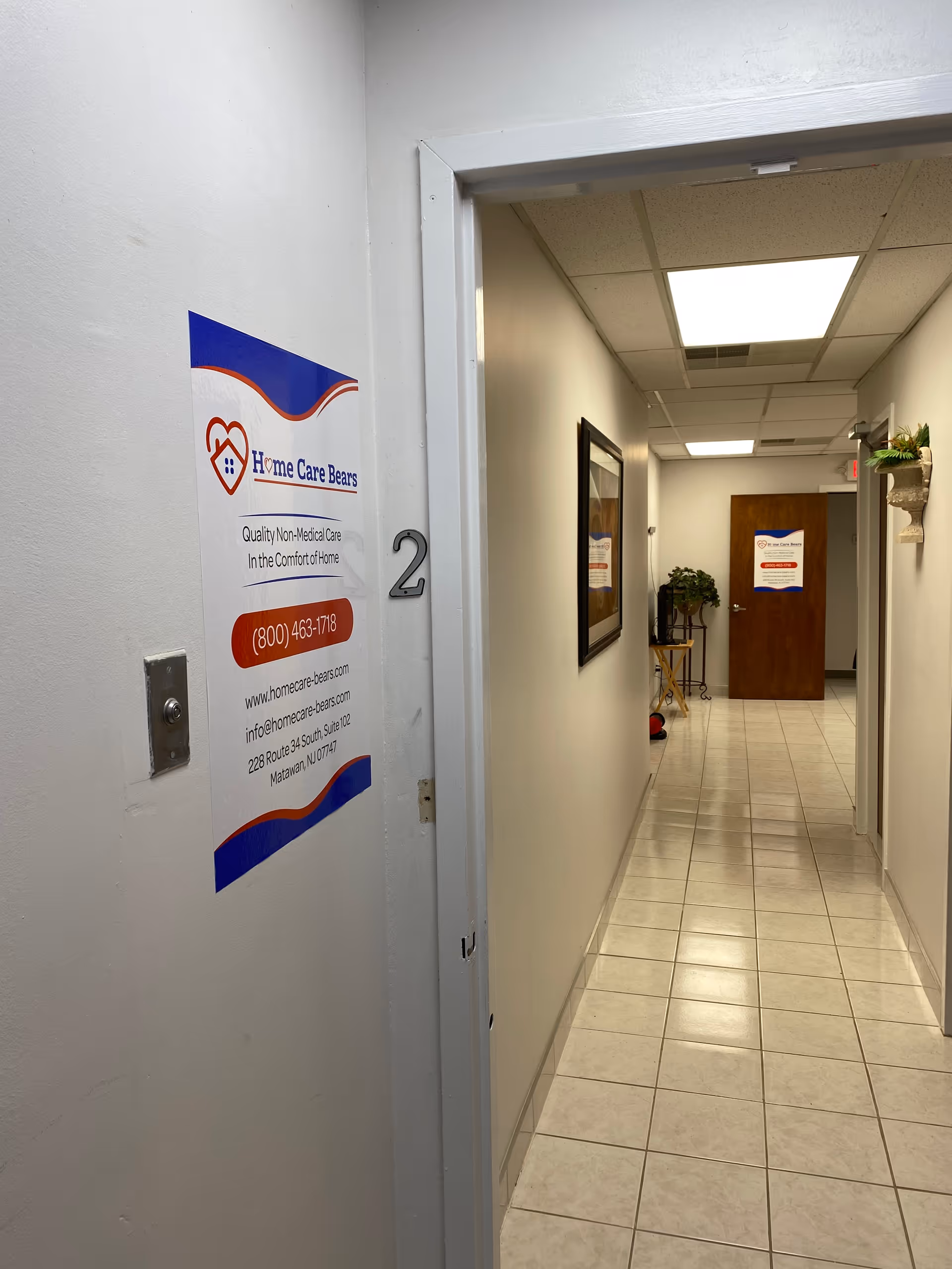 Interior hallway of a senior care facility with tiled floor and wall signage.