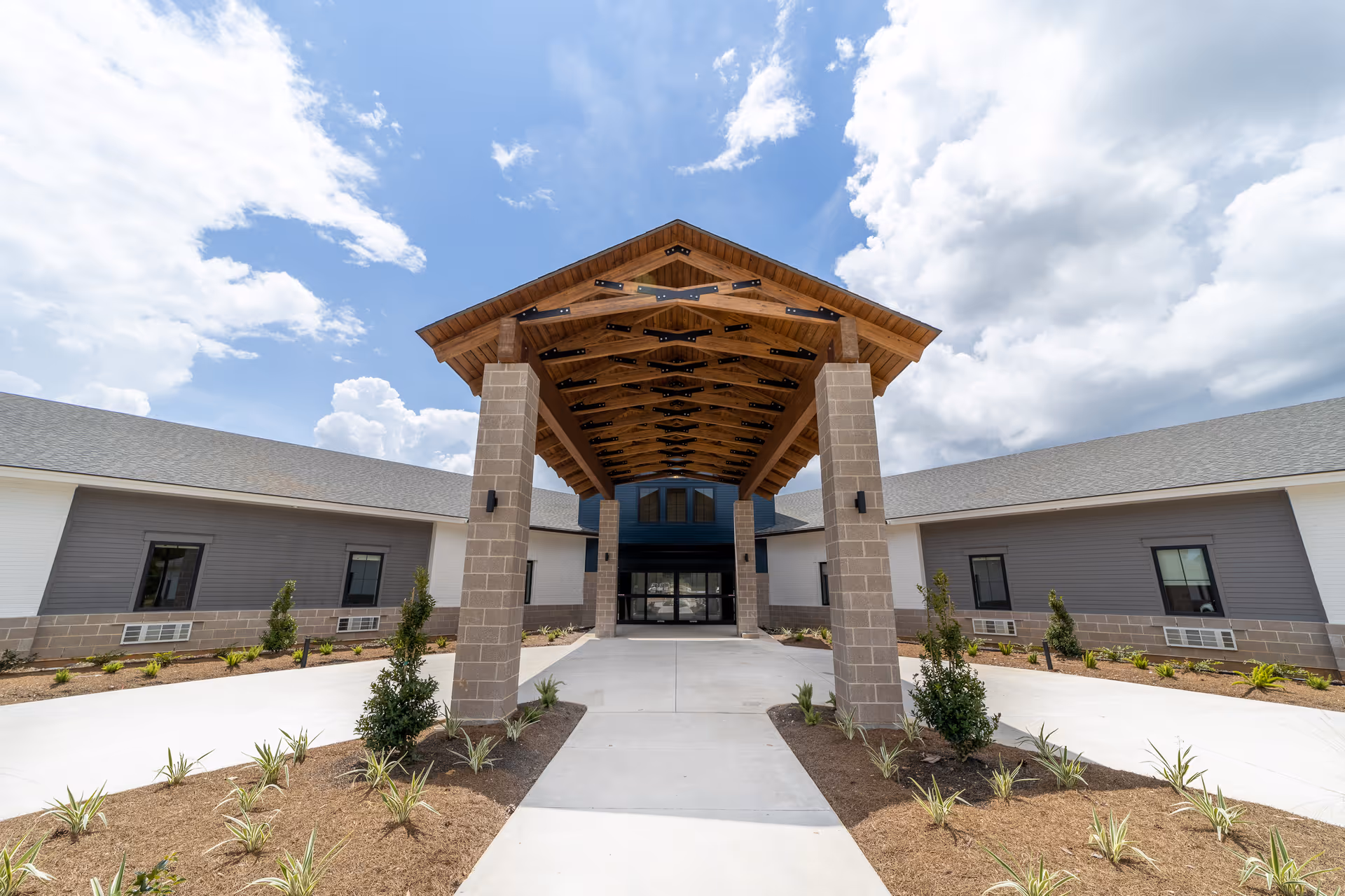 Wide view of the front entrance to a senior living facility with a wooden canopy.