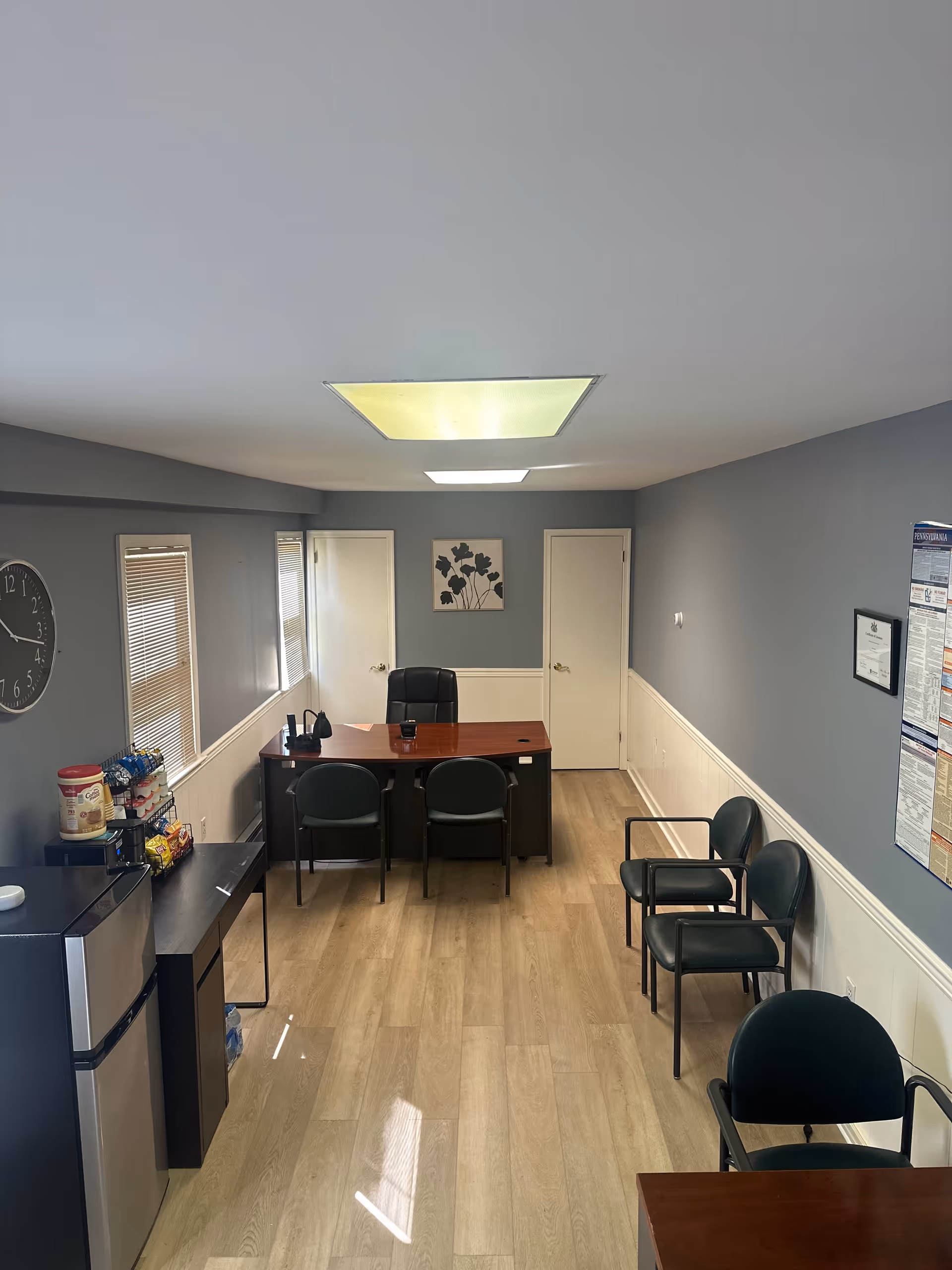 Interior reception area with desk, chairs, small kitchenette, and blue walls in a senior facility.