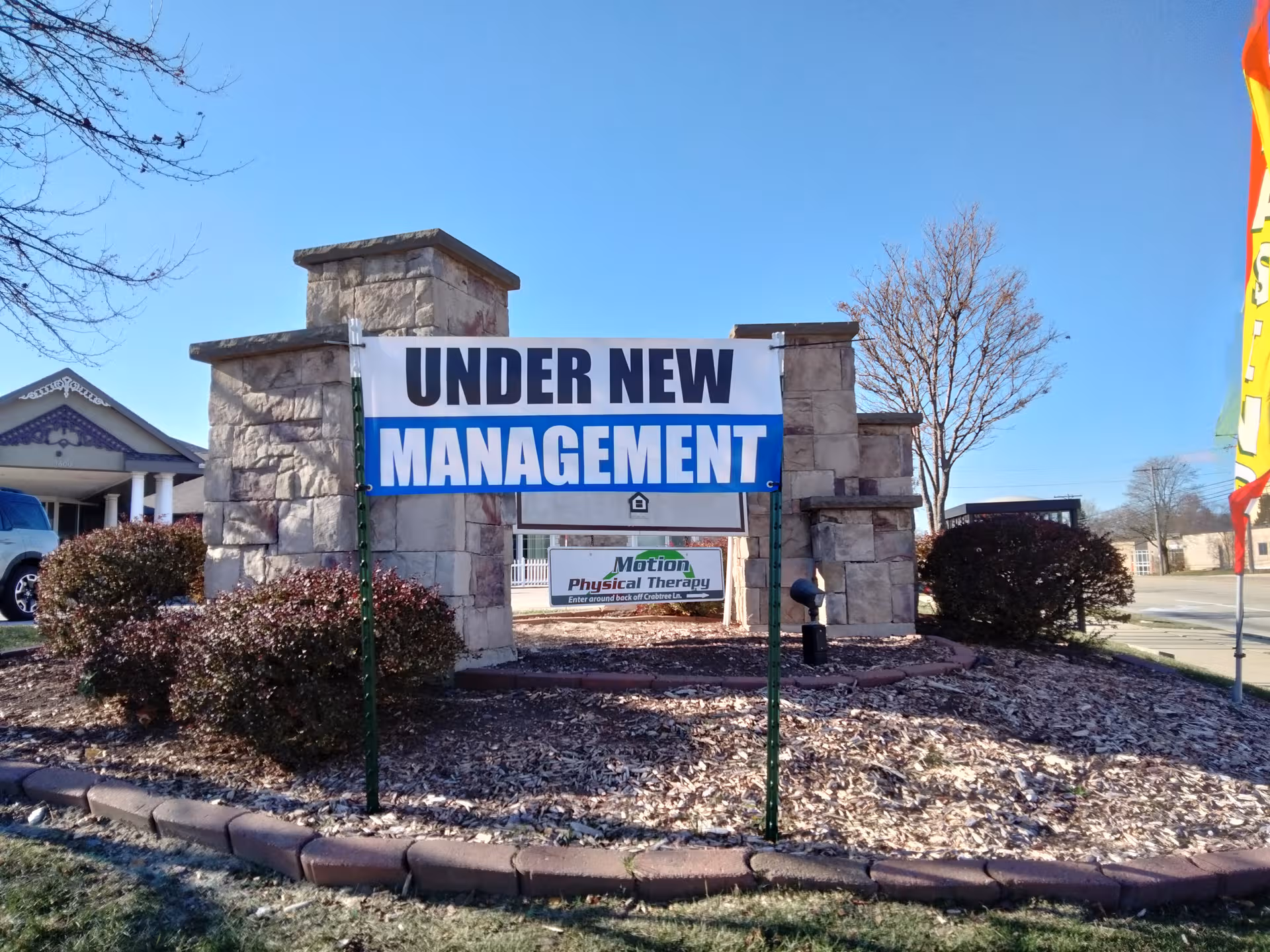 Stone entrance with a large 'Under New Management' sign in front of facility.