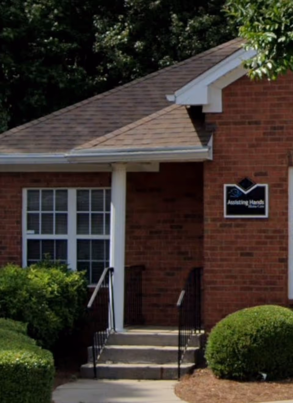 Brick exterior of a senior care facility with steps and signage.