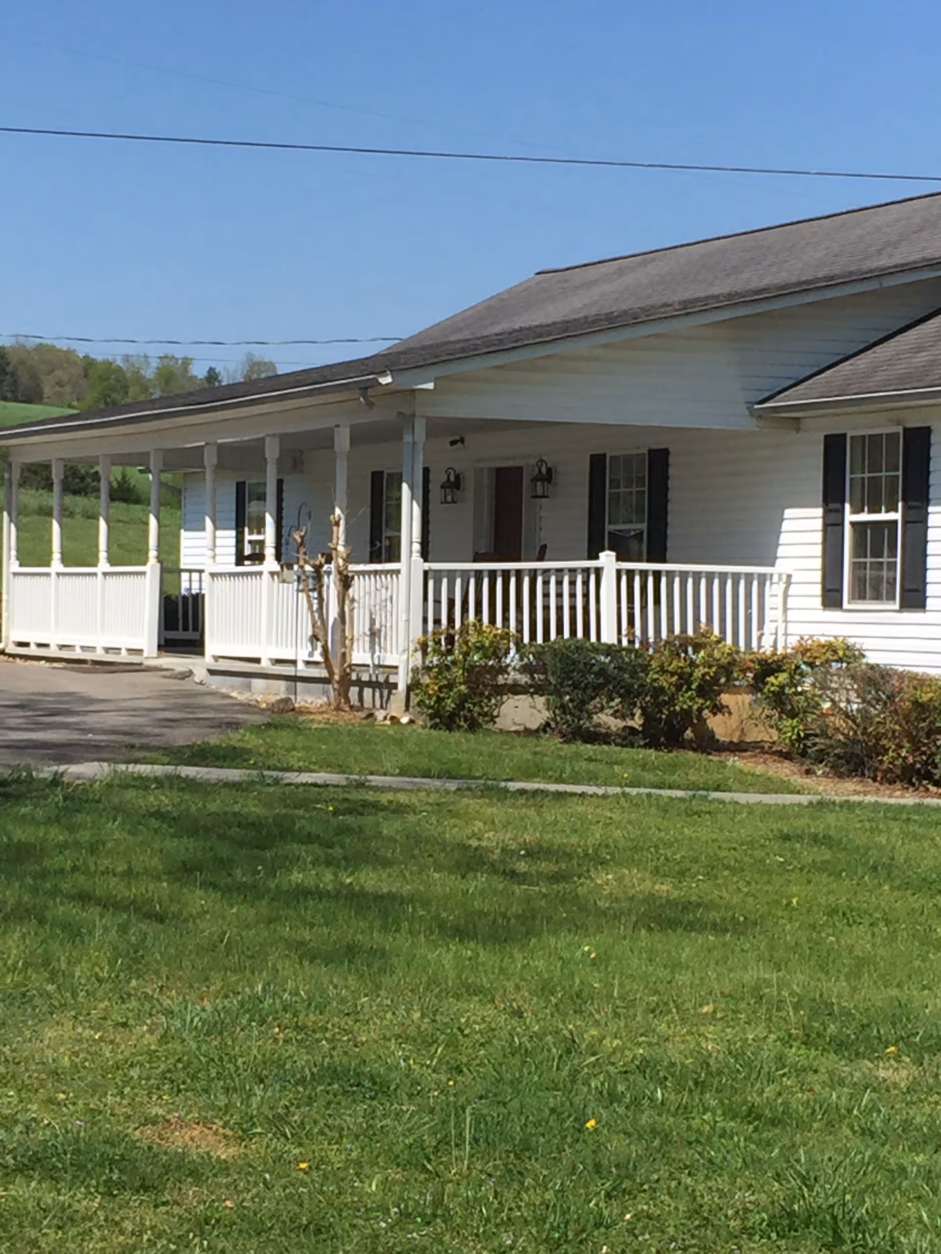 White, single-story Willow Acres facility with a long porch and green lawn.
