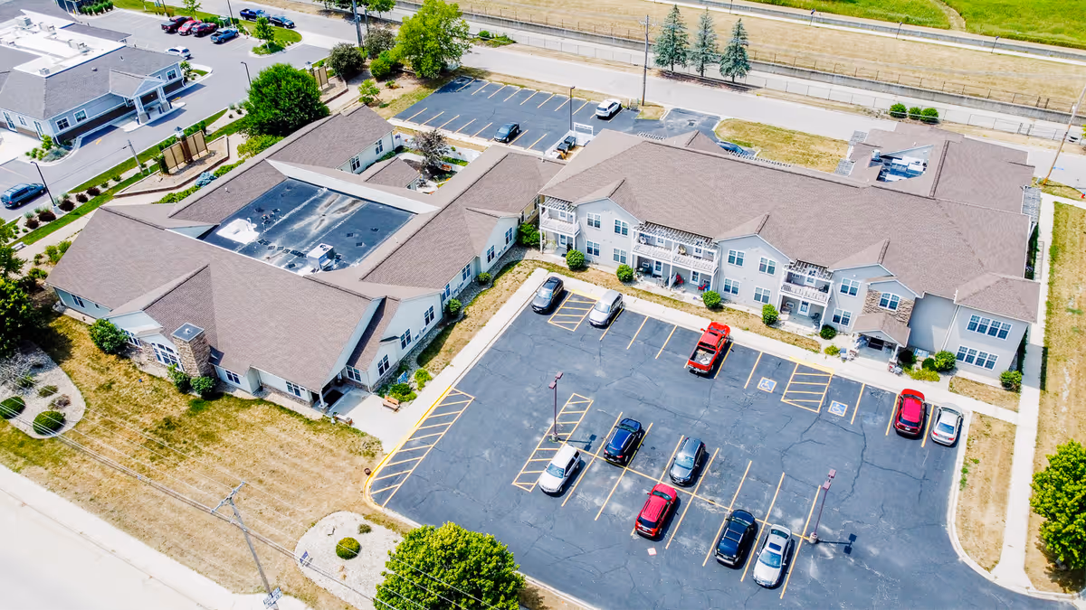 Aerial view of a multi-wing senior living campus with a large parking lot.