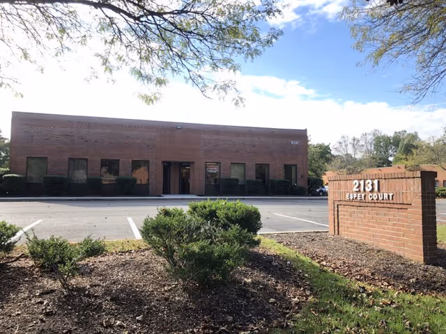 Brick exterior of a senior care facility with a parking lot and sign.