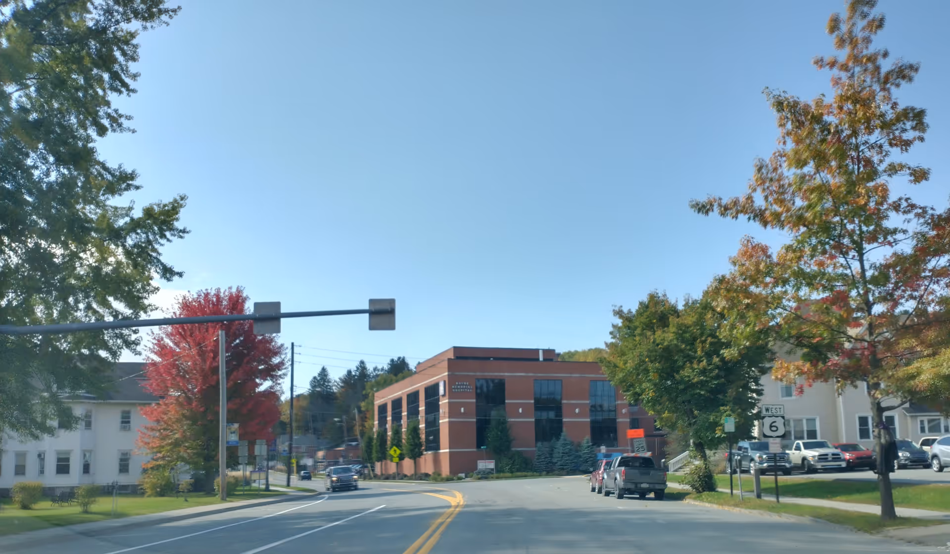 Street view of a brick building with trees and parked cars.