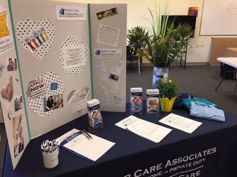 Harbor Care Associates info booth with brochures and posters on a navy table.