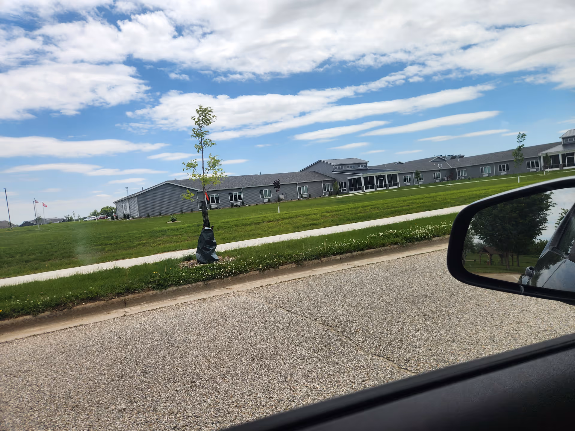 Exterior view of a single-story senior living campus with green lawn and blue sky.