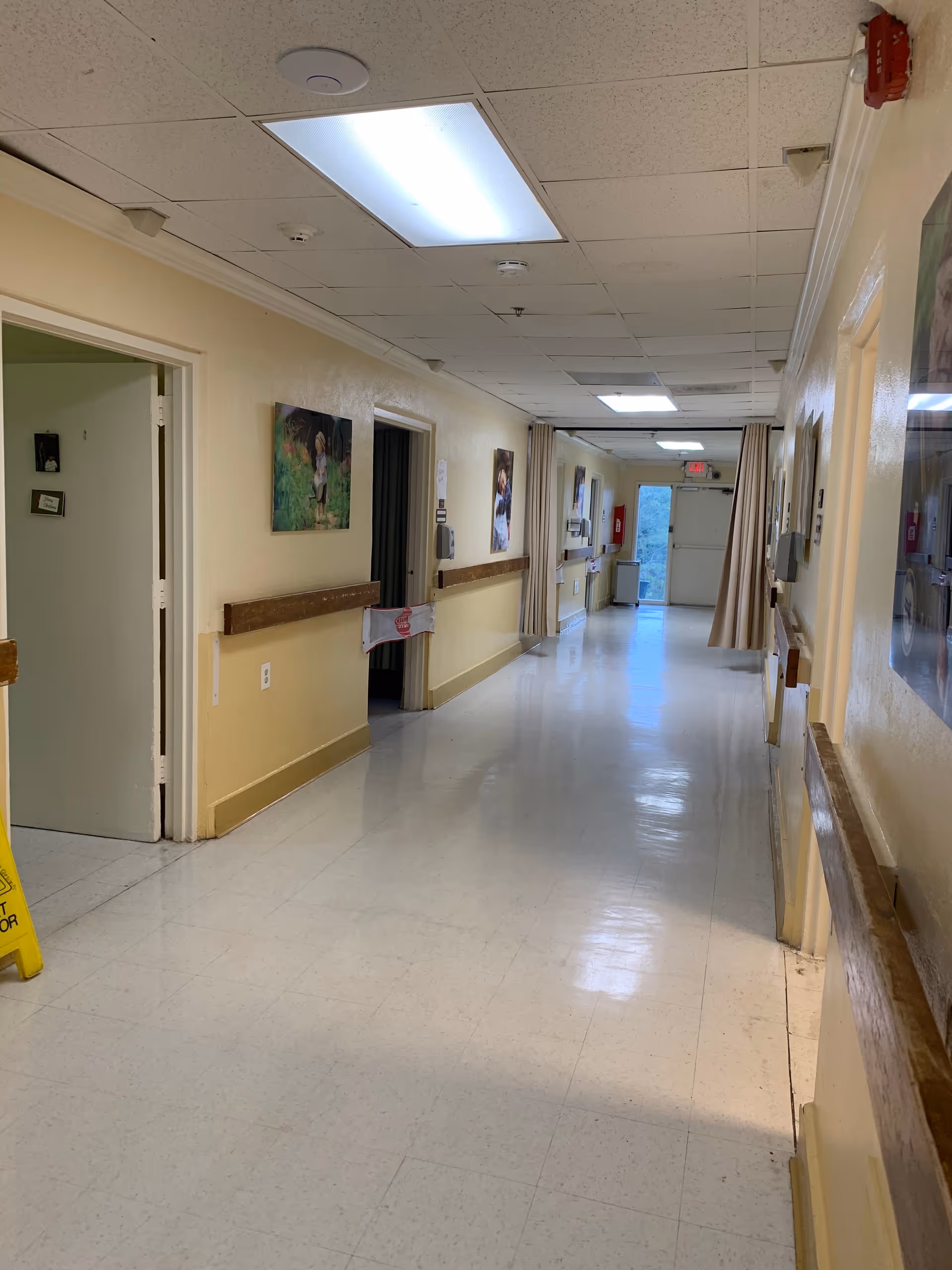 Long hallway inside Evergreen Health and Rehabilitation Center with rails and closed doors.