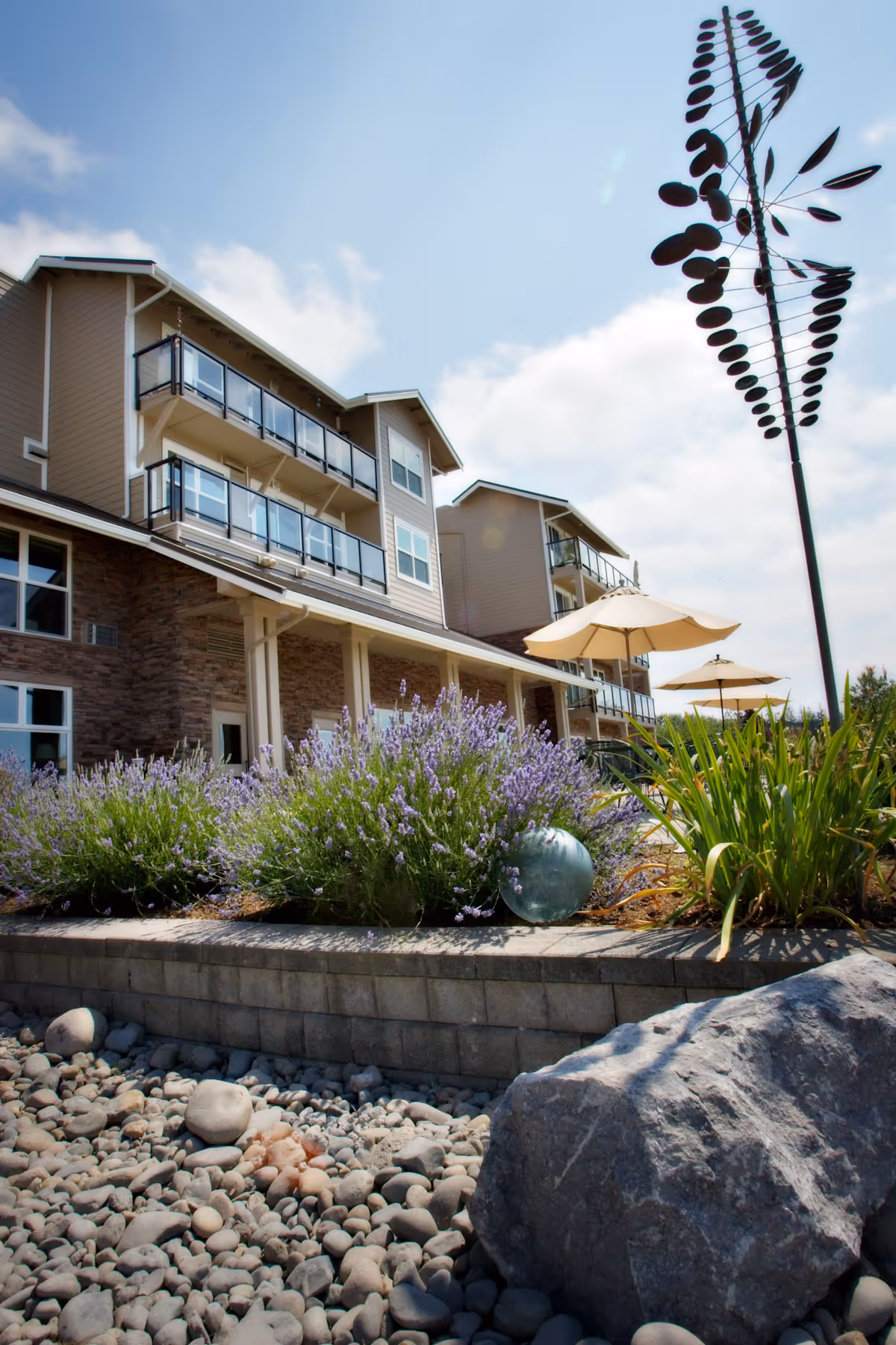 Exterior view of Crista Shores senior living building with balconies, lavender plants, and decorative rocks.