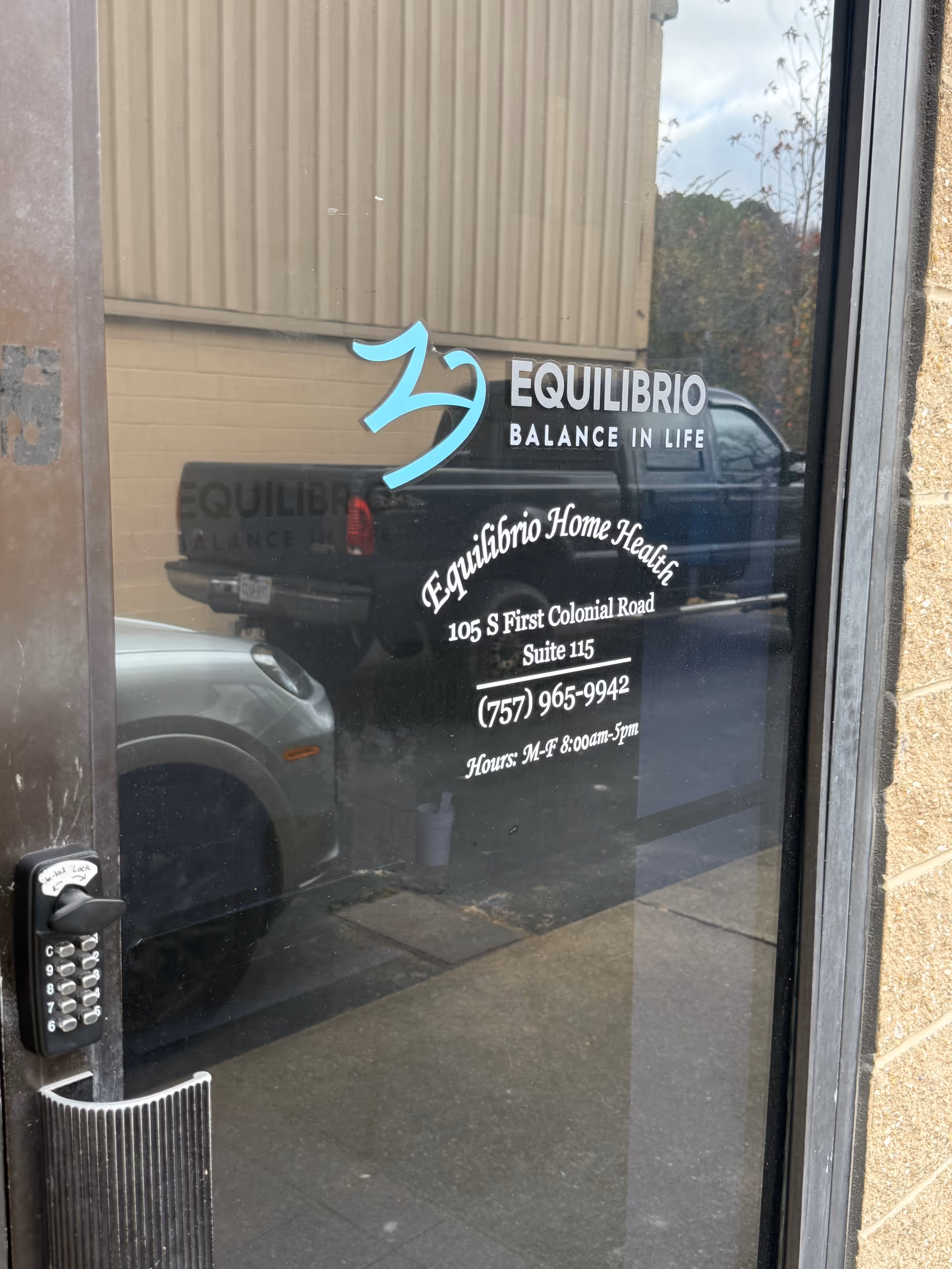 Glass entrance door displaying Equilibrio branding and address information.