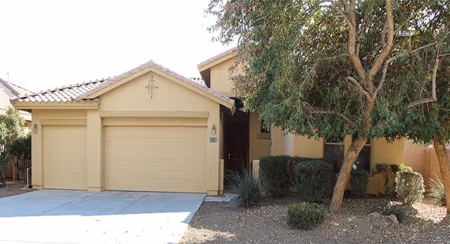 Front view of Caissa Assisted Living Home Inc building with two-car garage and desert landscaping.