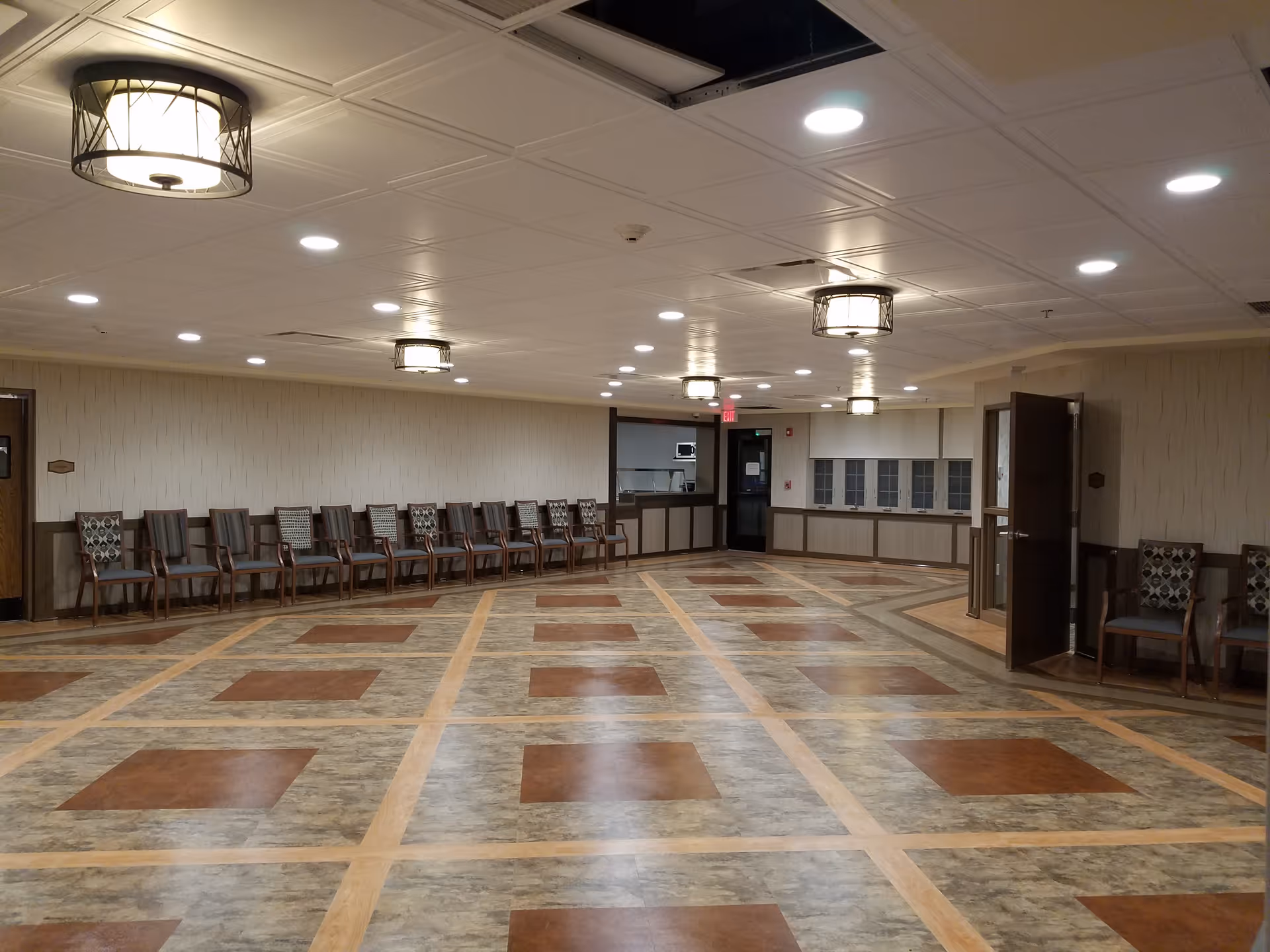 Spacious senior facility common room with chairs lined along the walls.