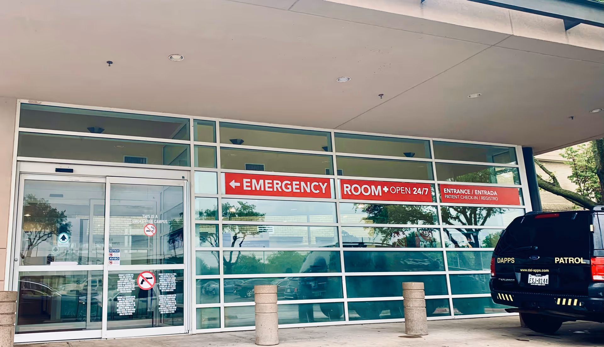Glass-front emergency entrance of Crescent Regional Hospital with red ER sign and a patrol van.