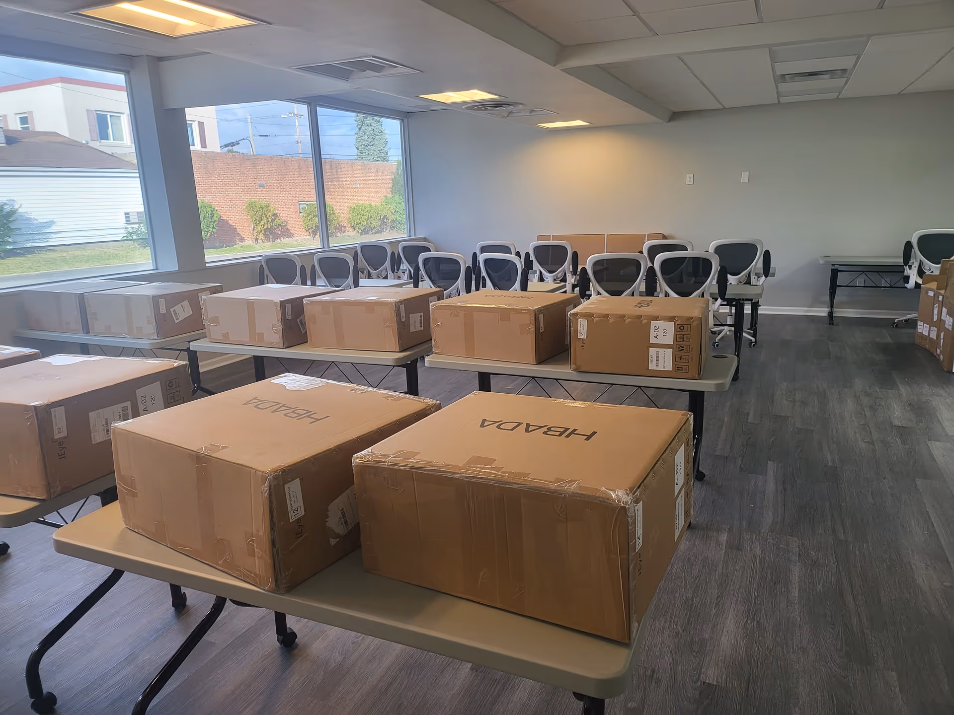 Interior room with tables stacked with cardboard boxes and chairs along the back wall.