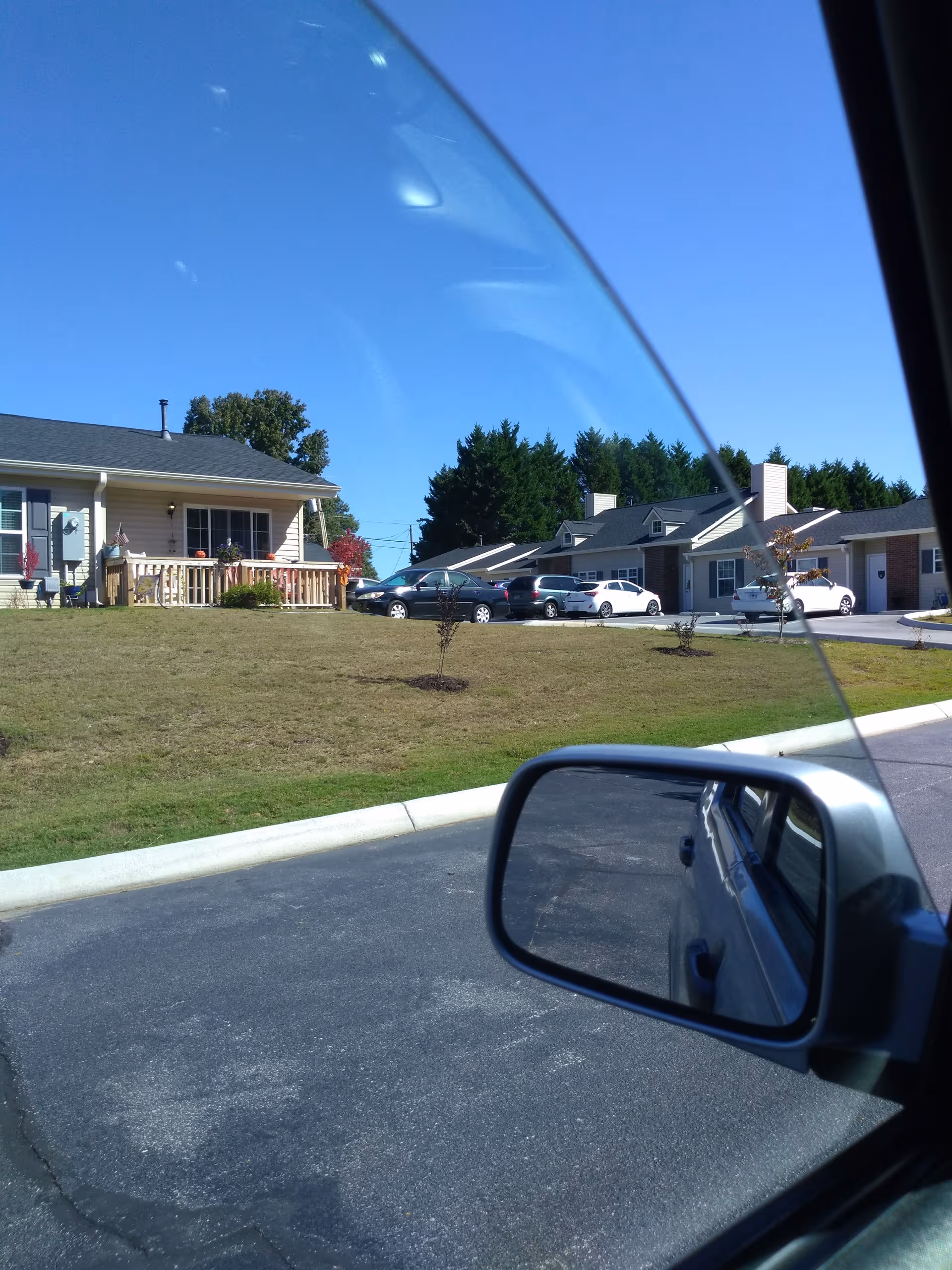 Exterior view of senior living cottages with parked cars along a driveway.