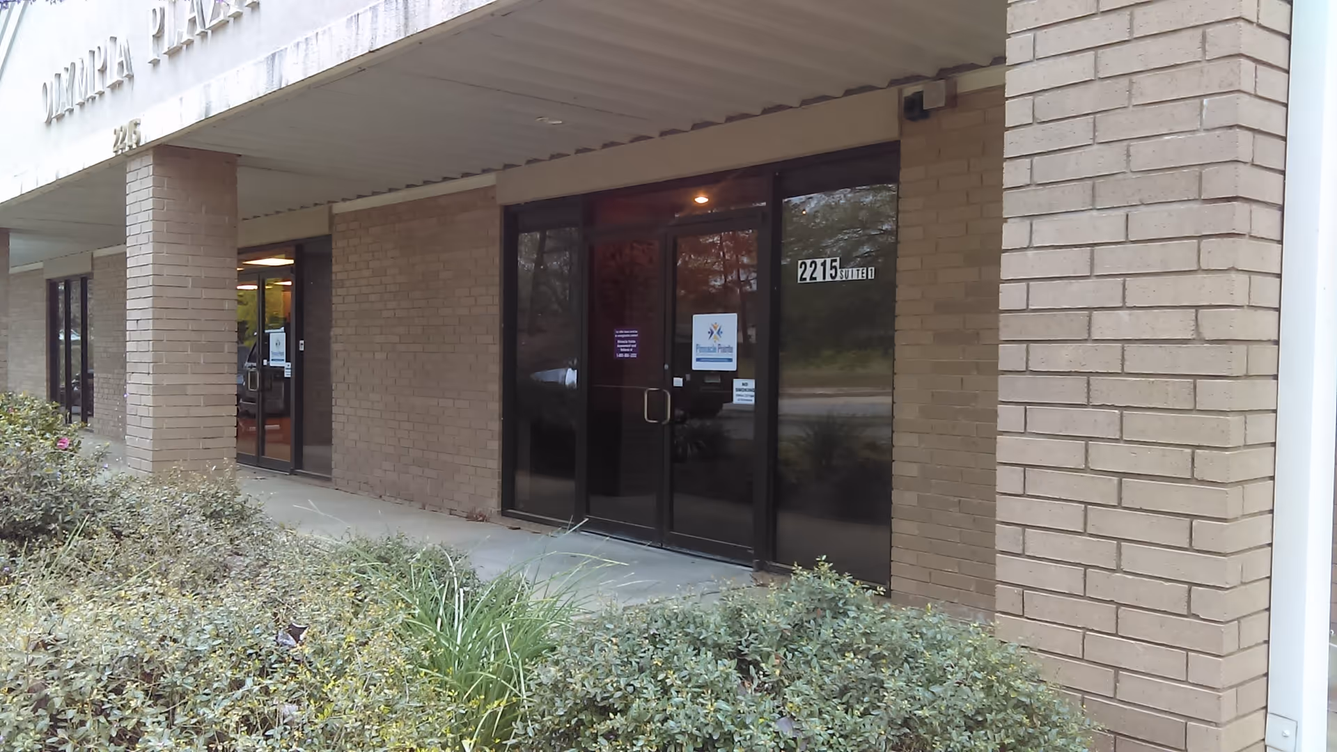 Exterior view of the building entrance with glass doors and brick facade.