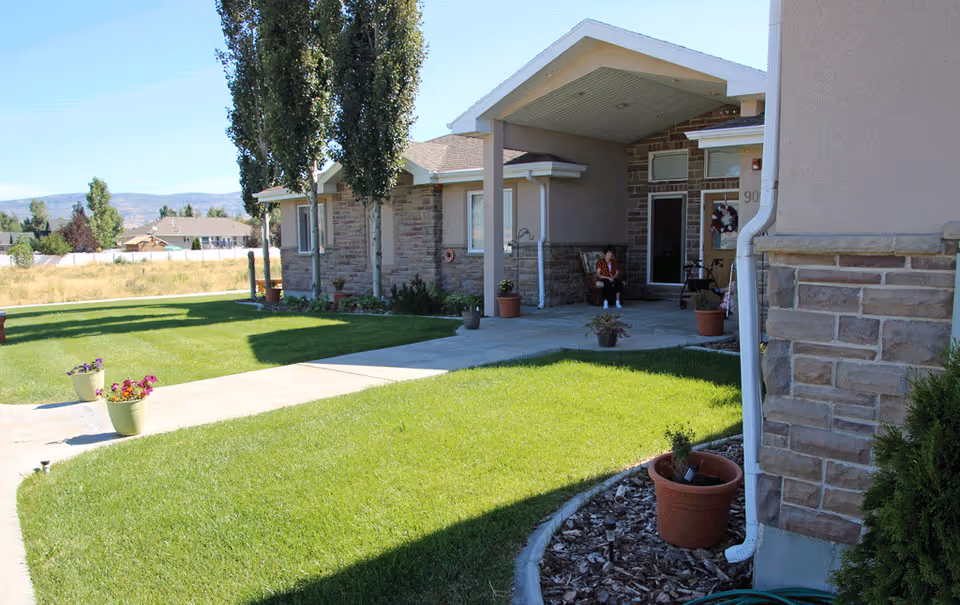Front exterior of a senior living facility with a porch and a resident seated.