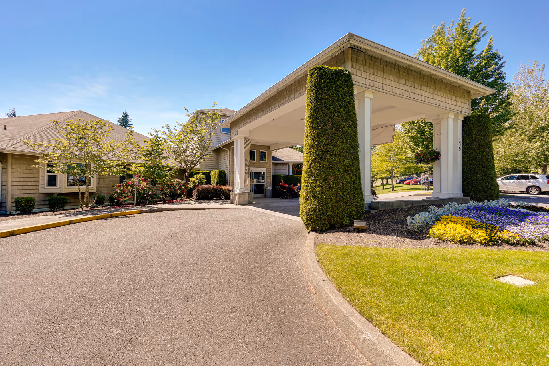 Exterior view of a senior living center with a covered entrance and landscaped grounds.