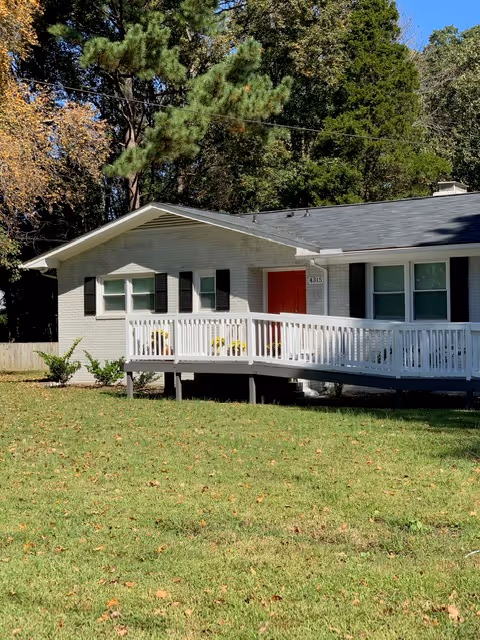 White single-story building with a red front door and wraparound porch.