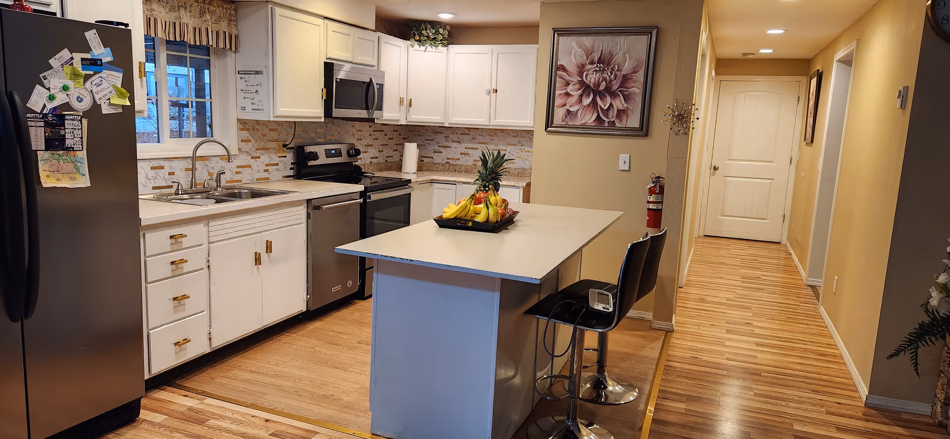 Bright kitchen with island, white cabinets, stainless appliances, and a fruit bowl on the island.