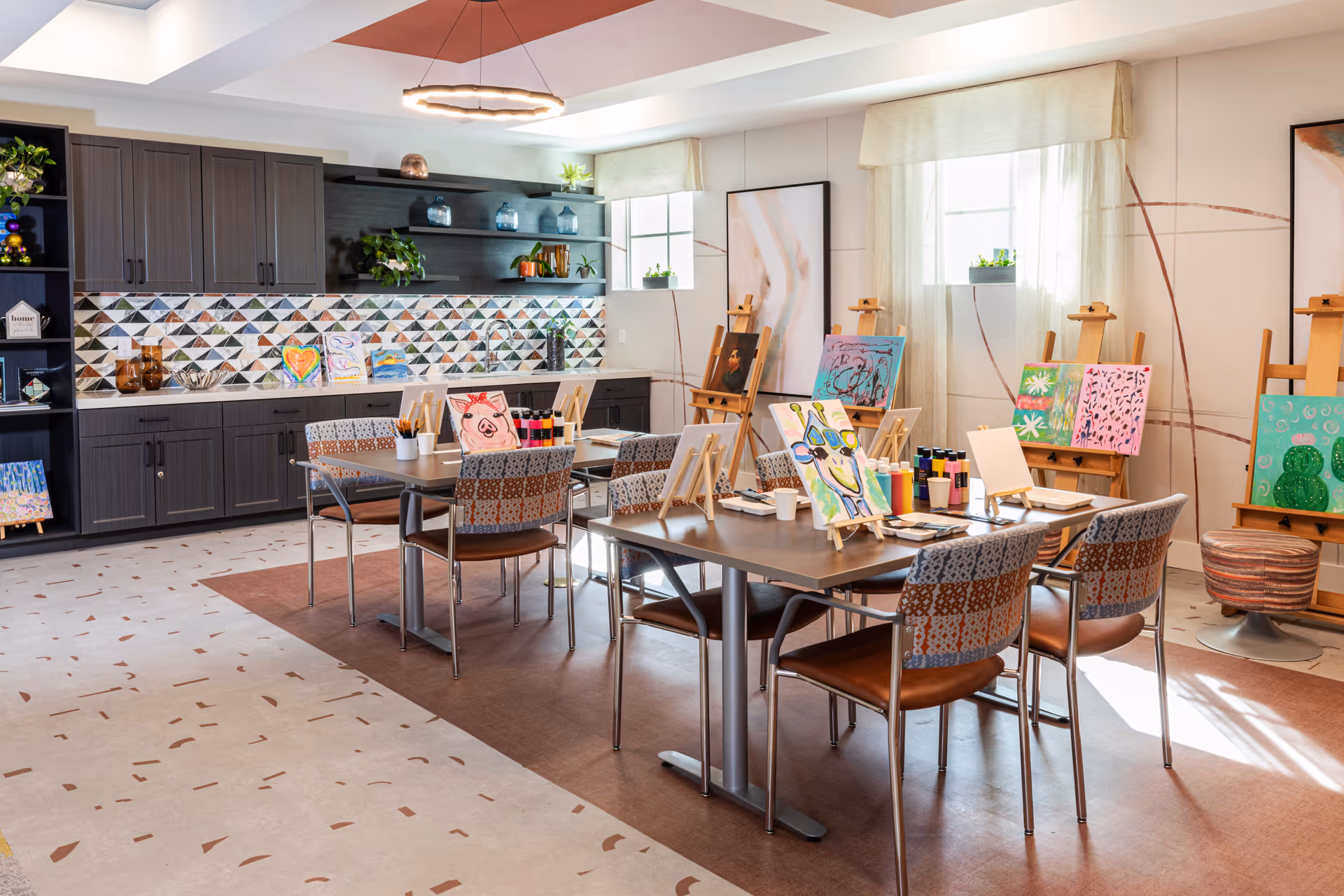 Art studio in a senior living facility with easels, tables, and colorful paintings.